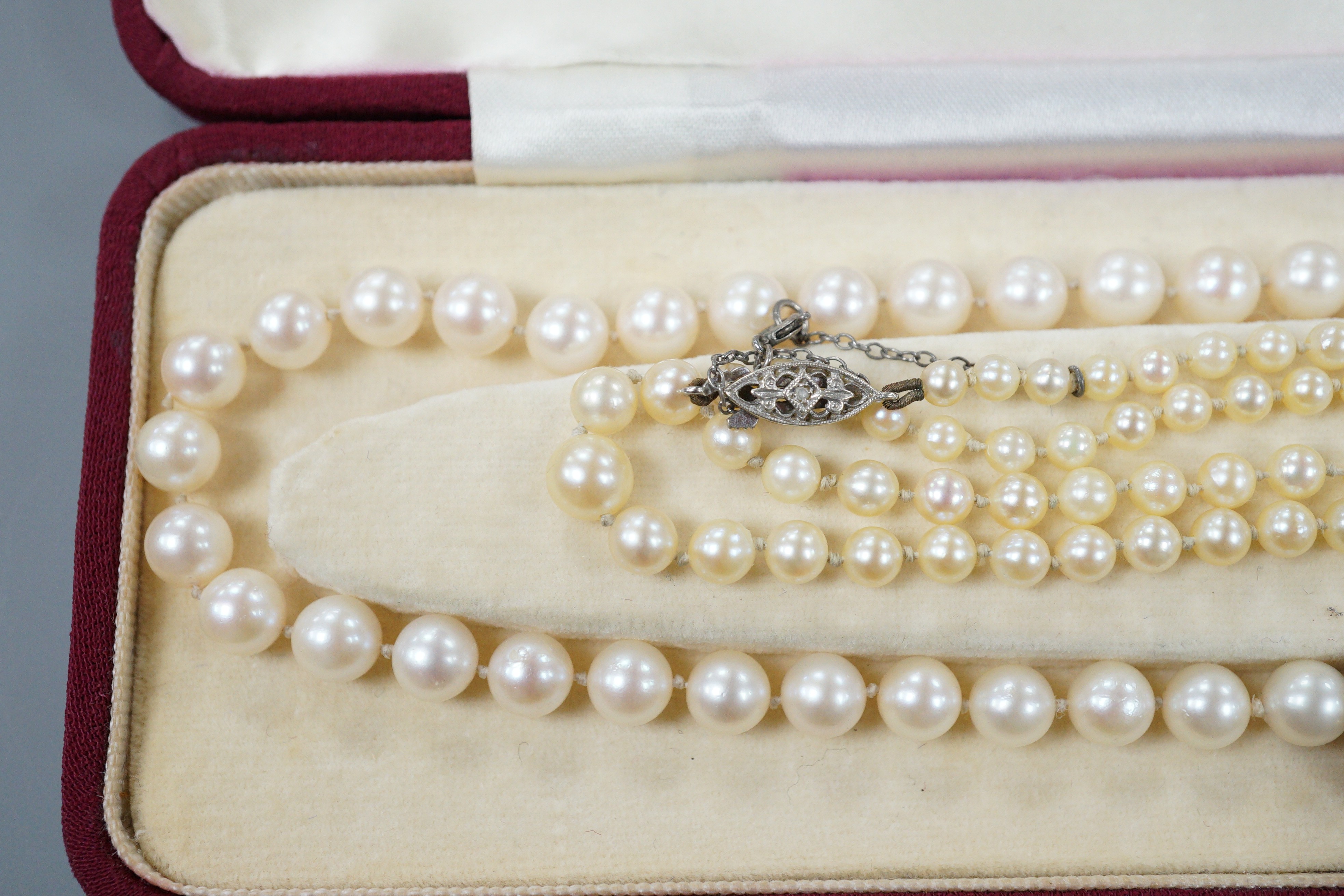 A modern single strand cultured pearl necklace, with 9ct, amethyst and cultured pearl set ova clasp, 44cm and one other single strand graduated cultured pearl necklace, with diamond chi set 9ct white gold clasp, 50cm.